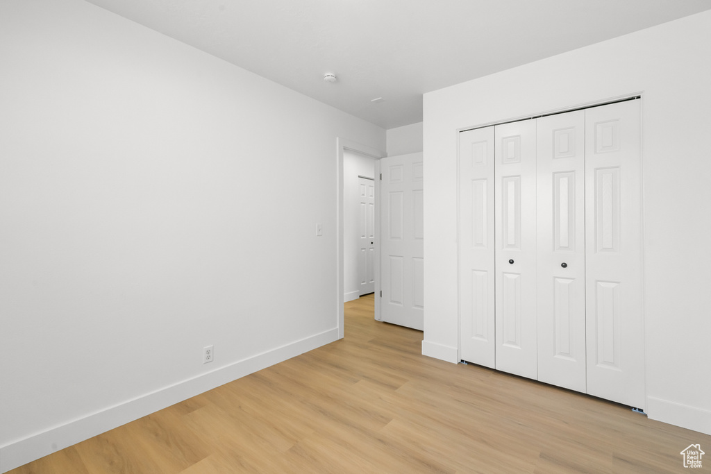 Unfurnished bedroom with light wood-style floors and a closet