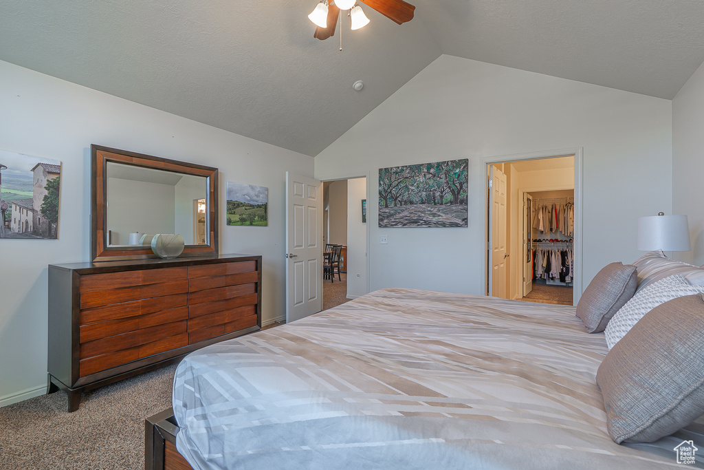 Carpeted bedroom with a ceiling fan and high vaulted ceiling