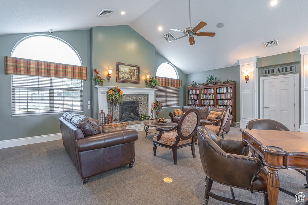 Carpeted living room with a ceiling fan, a stone fireplace, high vaulted ceiling, and recessed lighting