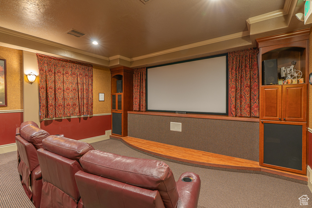 Carpeted home theater room with crown molding and recessed lighting