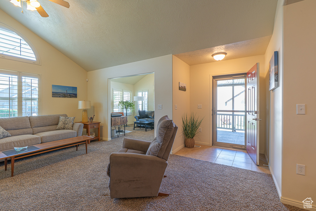 Carpeted living room with plenty of natural light, a textured ceiling, tile patterned flooring, ceiling fan, and high vaulted ceiling