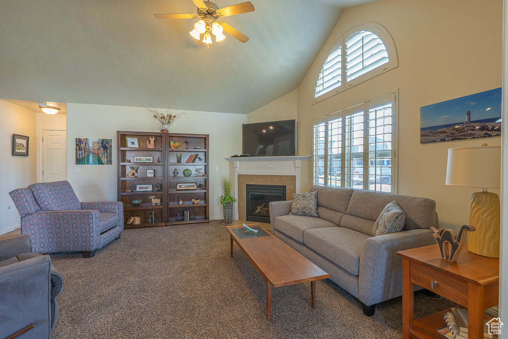 Living room with a tile fireplace, ceiling fan, carpet, and high vaulted ceiling