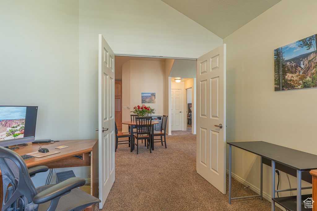 Carpeted office space featuring vaulted ceiling