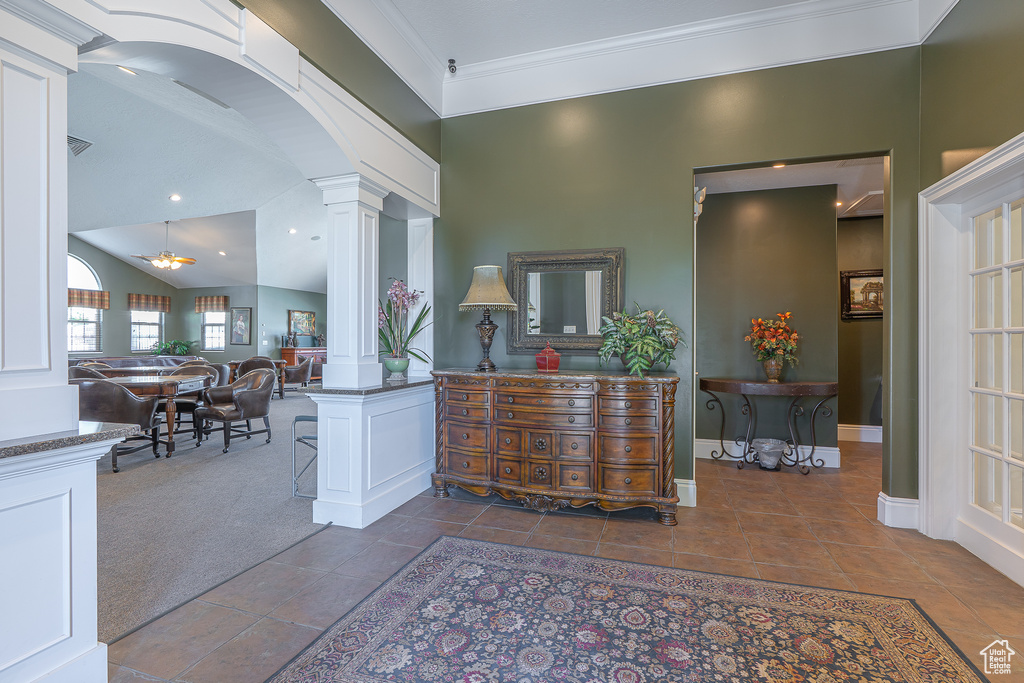 Interior space featuring decorative columns, arched walkways, crown molding, tile patterned floors, and lofted ceiling