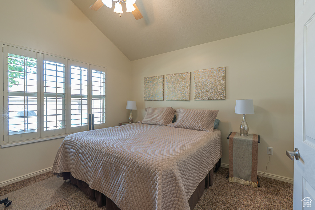 Carpeted bedroom with vaulted ceiling and ceiling fan