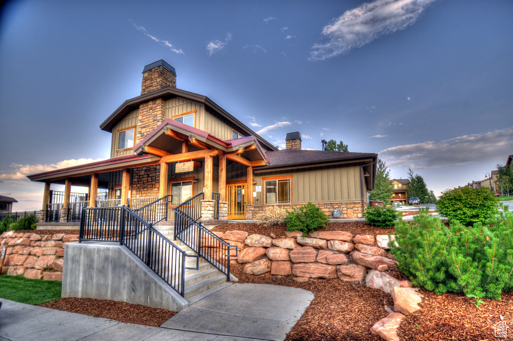 View of front of house with a chimney, a porch, board and batten siding, and stone siding