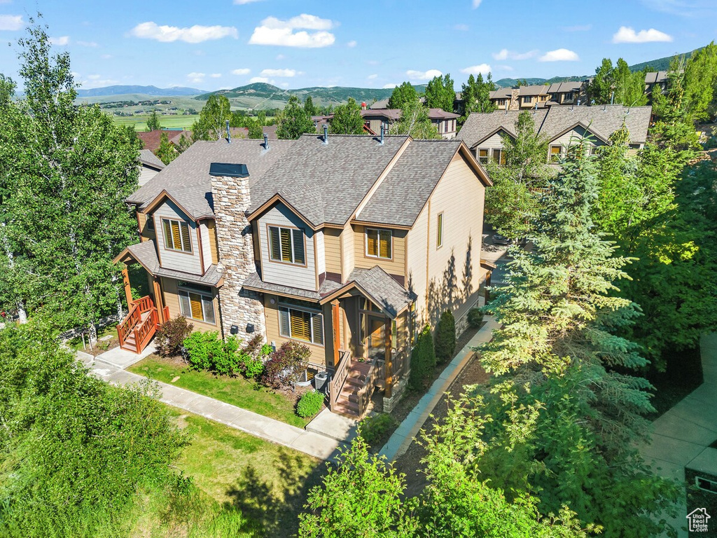View of front of home featuring a chimney, a shingled roof, and a mountain view
