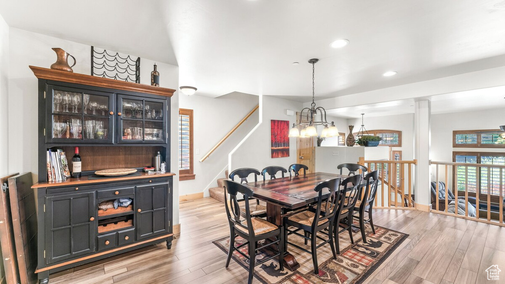 Dining area featuring light wood-style floors, a chandelier, a bar, and recessed lighting