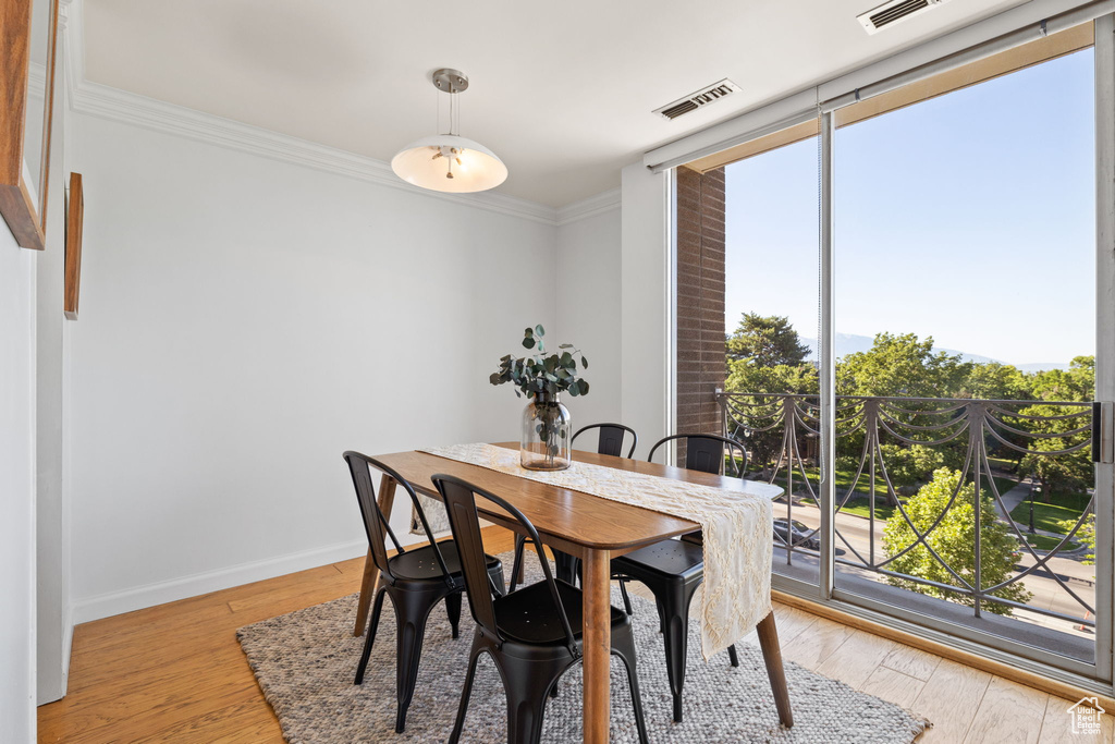 Dining area with crown molding and light wood-style flooring