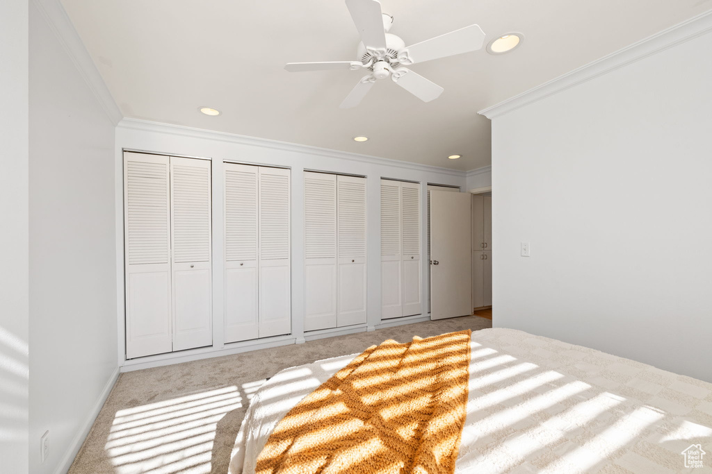 Unfurnished bedroom with crown molding, carpet floors, multiple closets, recessed lighting, and ceiling fan
