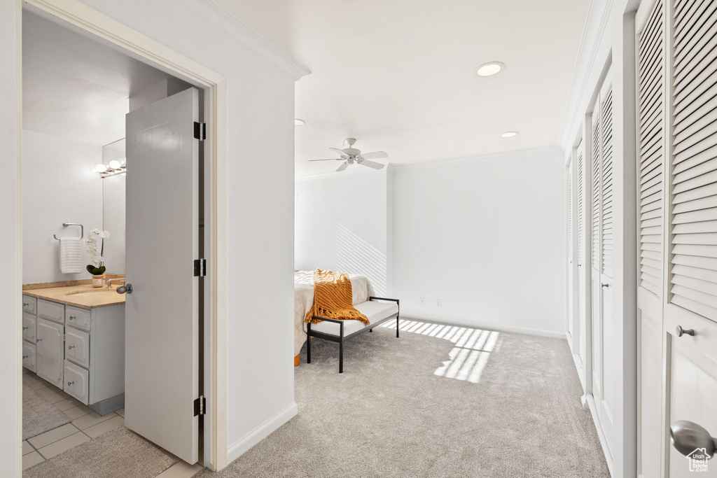 Hall with crown molding, recessed lighting, light carpet, and light tile patterned flooring