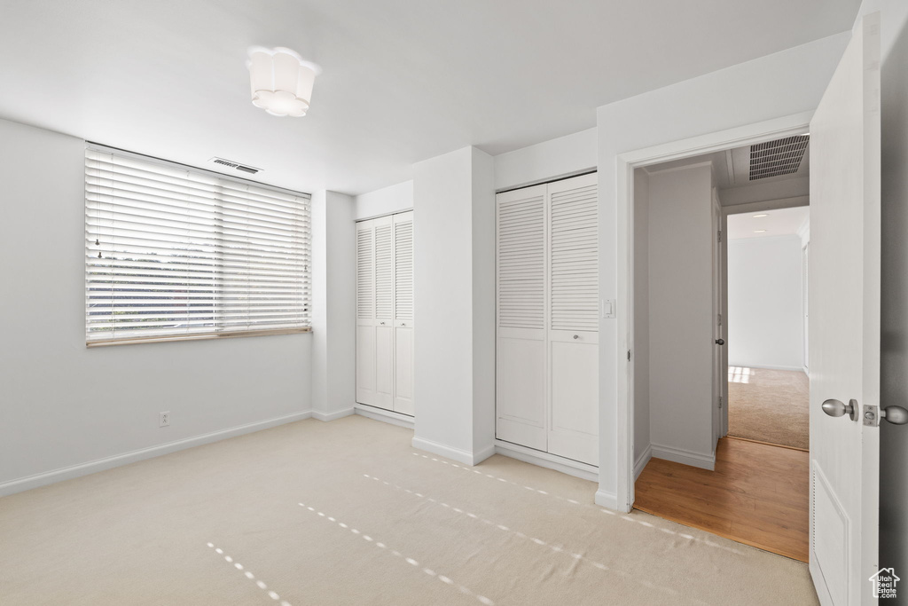 Unfurnished bedroom featuring carpet flooring and two closets