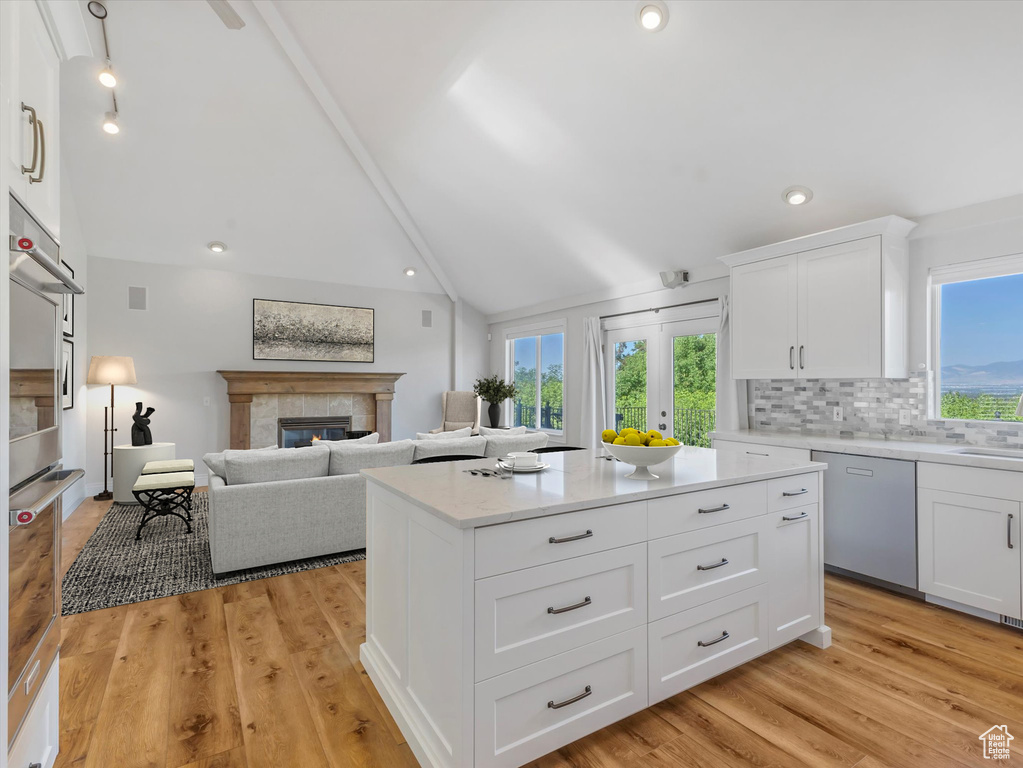 Kitchen featuring dishwasher, healthy amount of natural light, a tiled fireplace, decorative backsplash, and recessed lighting