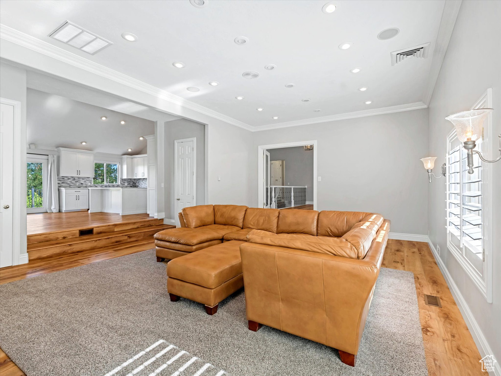 Living room with light wood-type flooring, recessed lighting, and ornamental molding