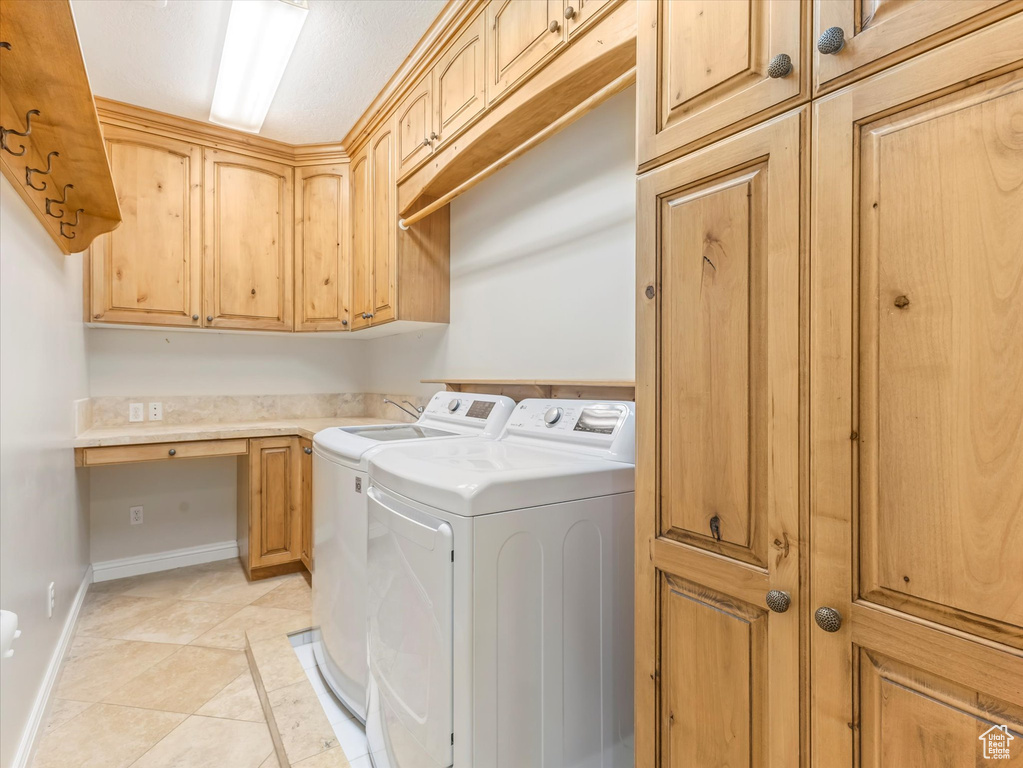 Laundry room with separate washer and dryer, cabinet space, light tile patterned floors, inlaid floor details, and a desk