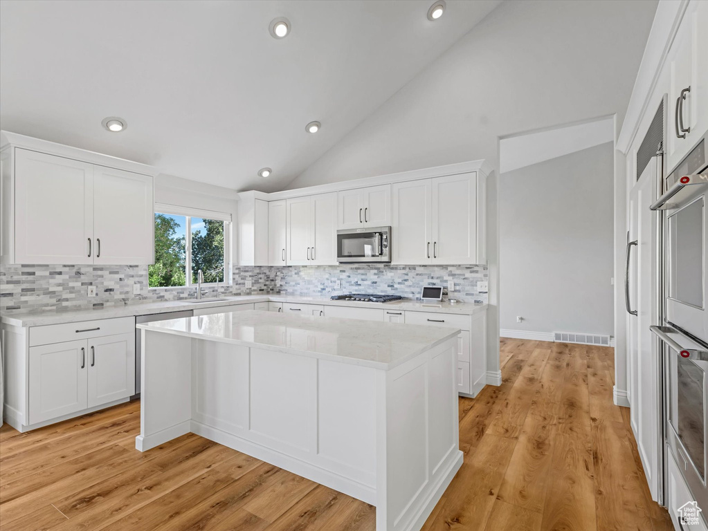 Kitchen featuring appliances with stainless steel finishes, tasteful backsplash, light countertops, white cabinetry, and recessed lighting