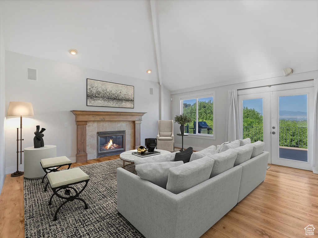 Living area featuring a tile fireplace, light wood-type flooring, and high vaulted ceiling