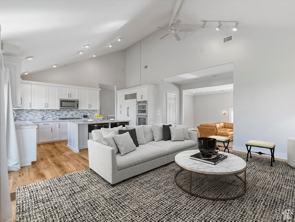 Living room with ceiling fan, high vaulted ceiling, and light wood-style floors