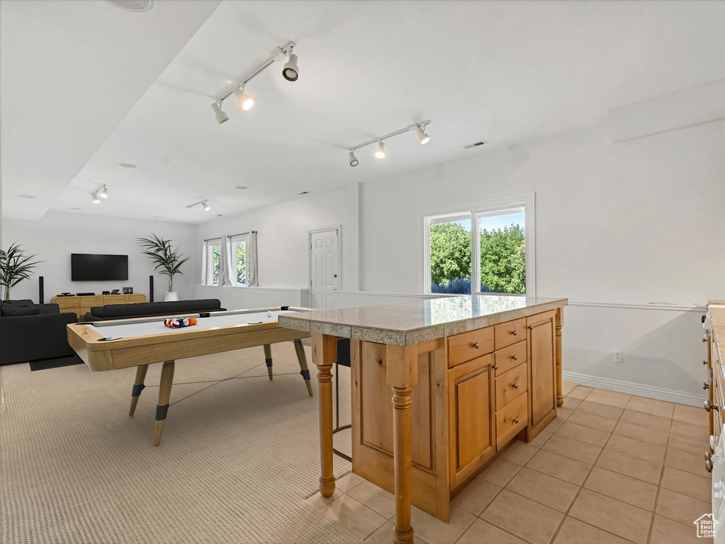 Kitchen featuring open floor plan, light tile patterned floors, a kitchen island, and a breakfast bar