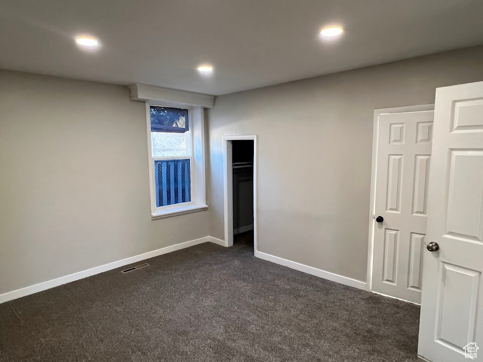 Unfurnished bedroom with dark colored carpet, recessed lighting, and a closet
