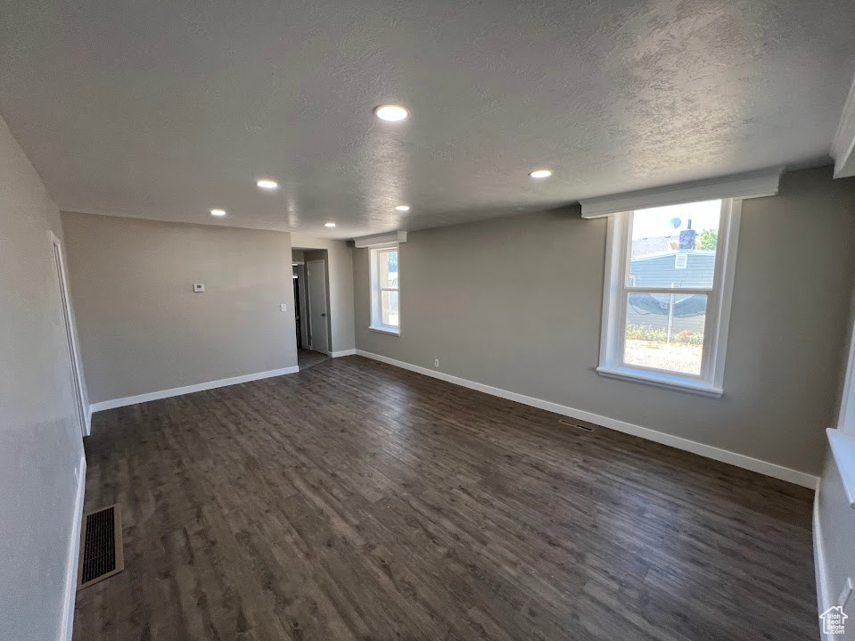 Spare room with dark wood-style flooring, recessed lighting, and a textured ceiling