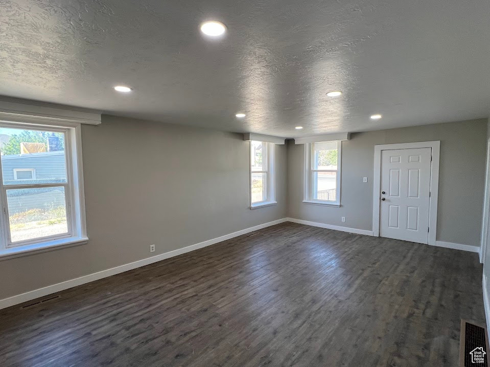 Empty room with dark wood finished floors, recessed lighting, and a textured ceiling