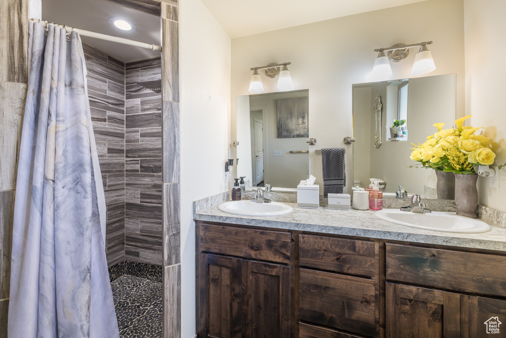Full bathroom featuring double vanity and a tile shower