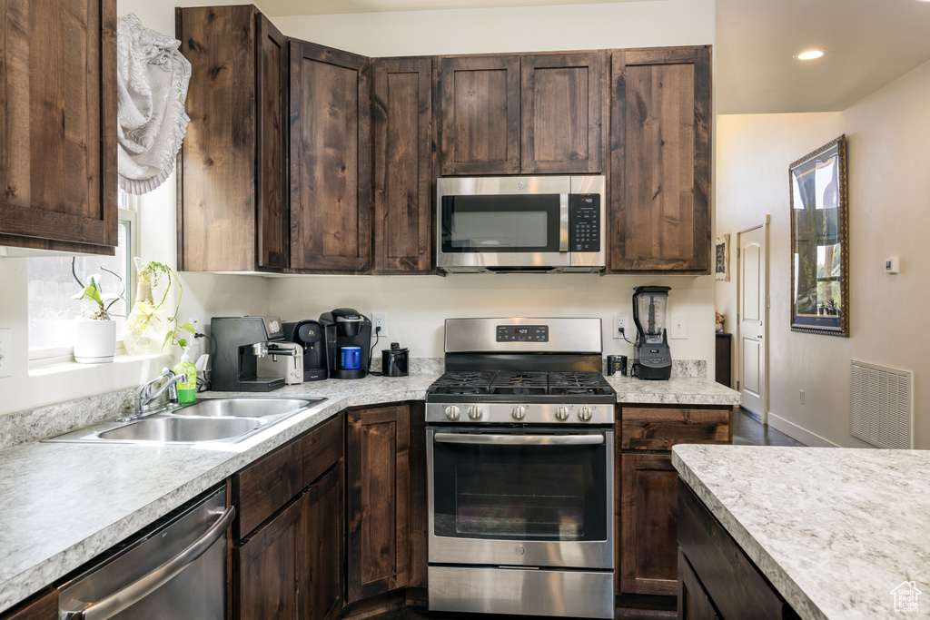 Kitchen featuring stainless steel appliances, dark brown cabinets, light countertops, and recessed lighting