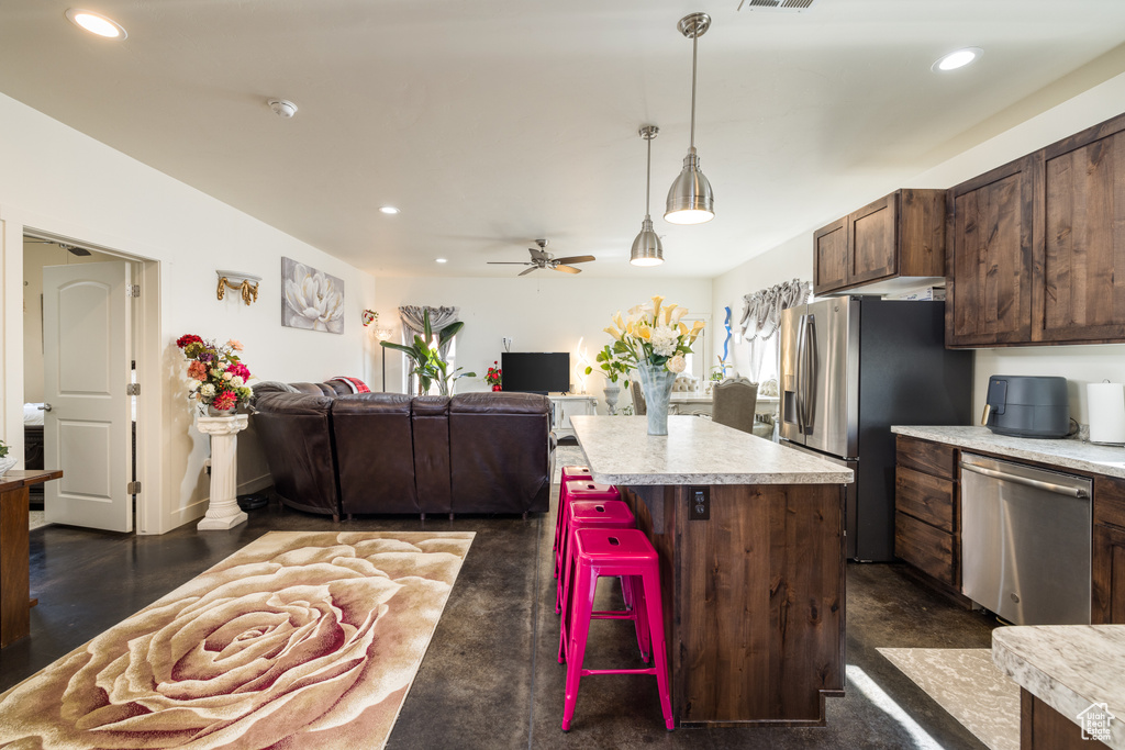 Kitchen with appliances with stainless steel finishes, light countertops, recessed lighting, open floor plan, and pendant lighting