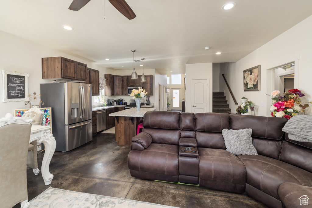 Living room with concrete flooring, stairway, recessed lighting, and a ceiling fan