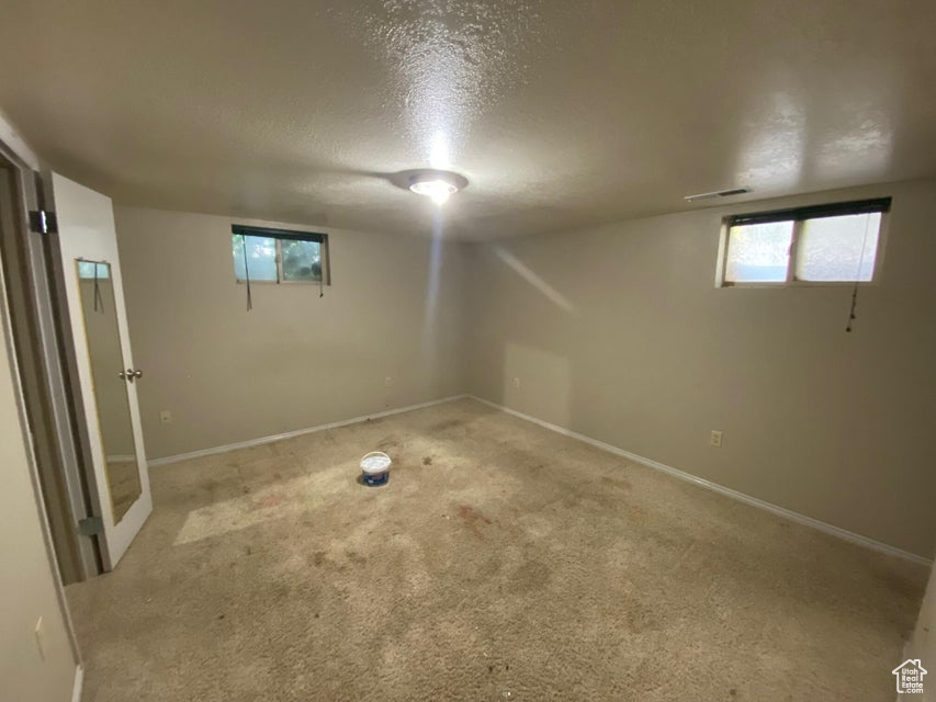 Below grade area featuring a textured ceiling and carpet flooring