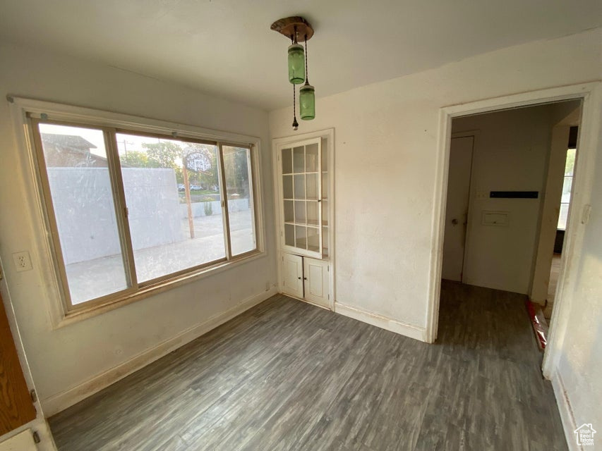 Unfurnished dining area with baseboards and dark wood-style flooring