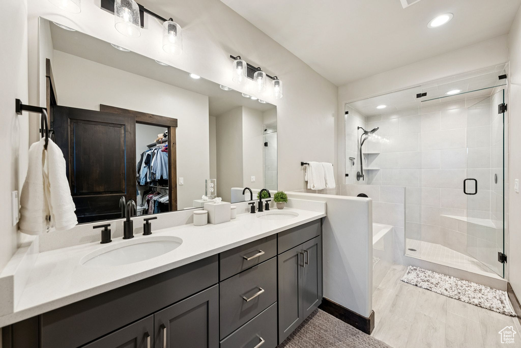 Full bathroom with double vanity, a stall shower, a bath, a spacious closet, and recessed lighting