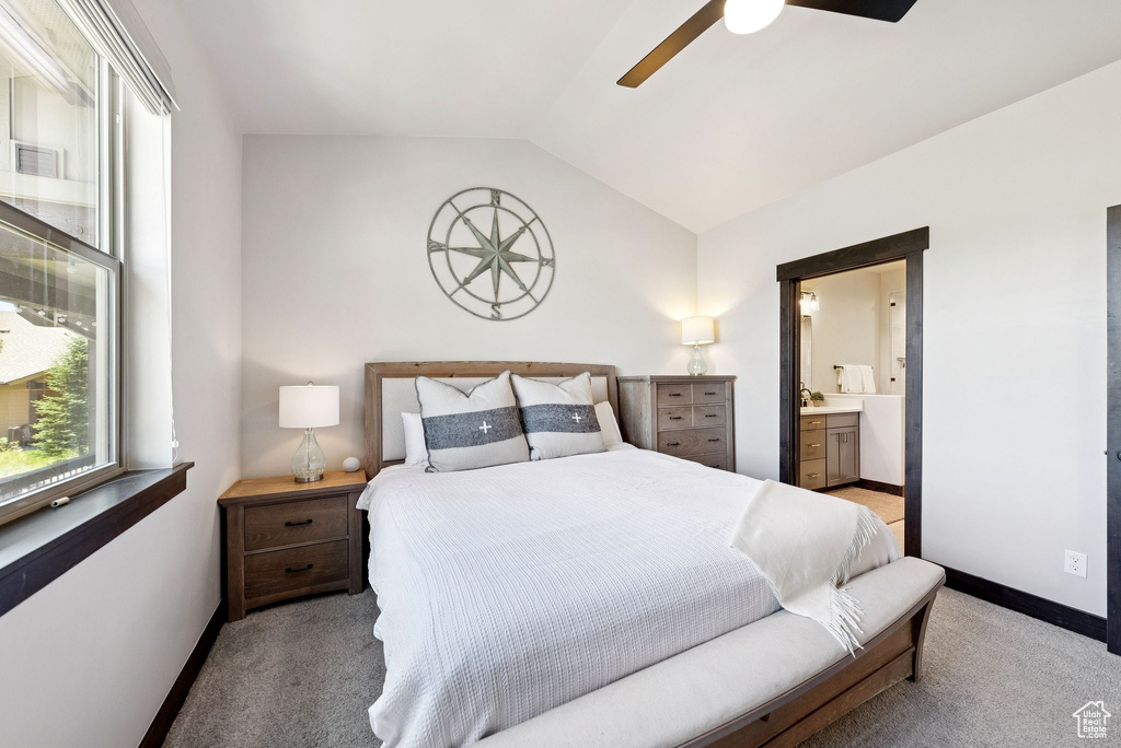 Bedroom with vaulted ceiling, light carpet, connected bathroom, and ceiling fan