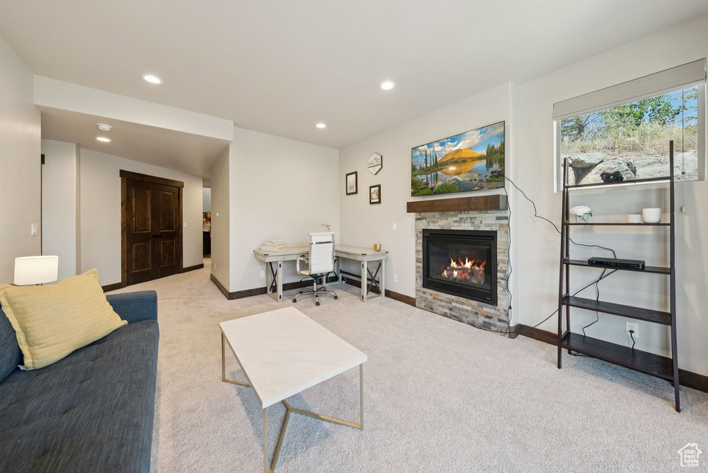 Living area with light carpet, a glass covered fireplace, recessed lighting, and a desk
