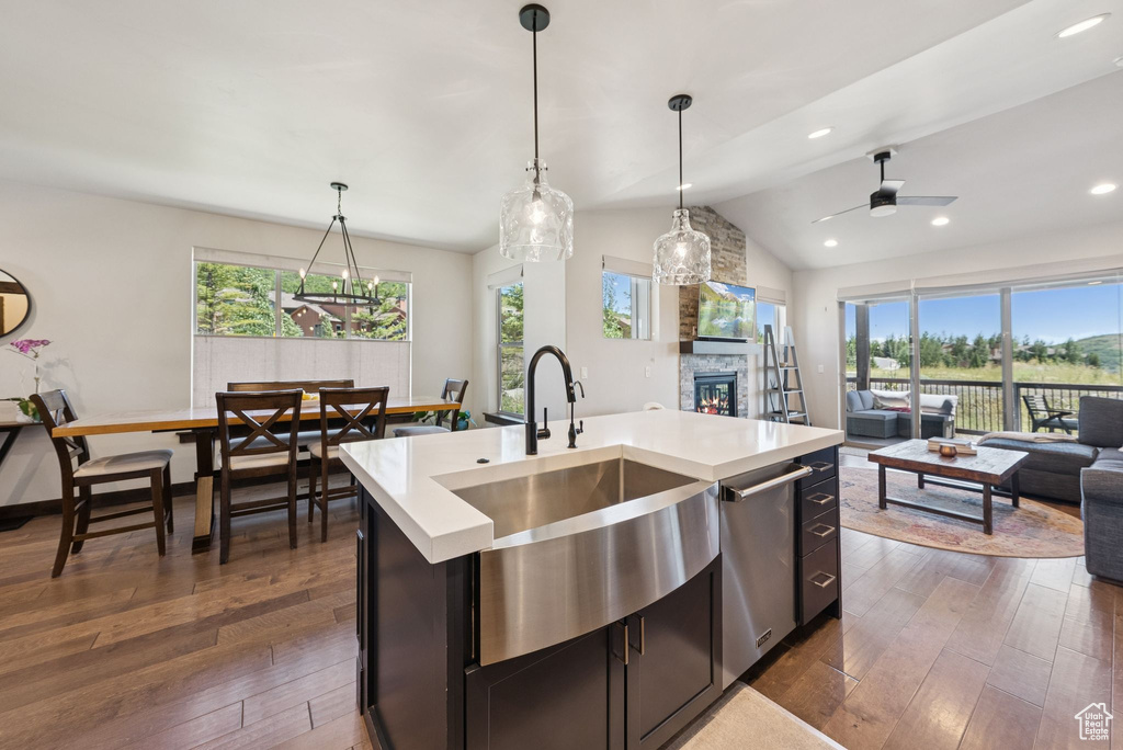 Kitchen featuring open floor plan, a fireplace, plenty of natural light, light countertops, and lofted ceiling