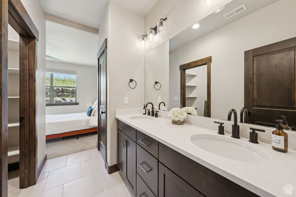 Full bathroom with double vanity, connected bathroom, tile patterned flooring, and a closet