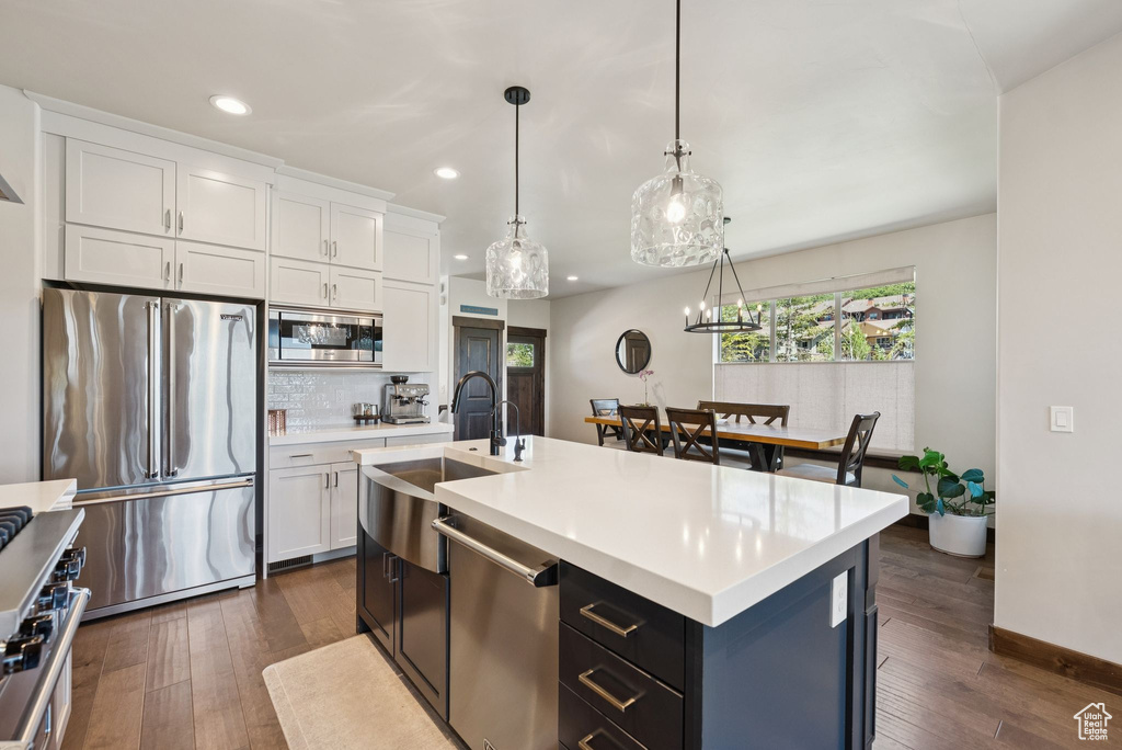Kitchen with stainless steel appliances, recessed lighting, light countertops, white cabinetry, and dark wood-type flooring