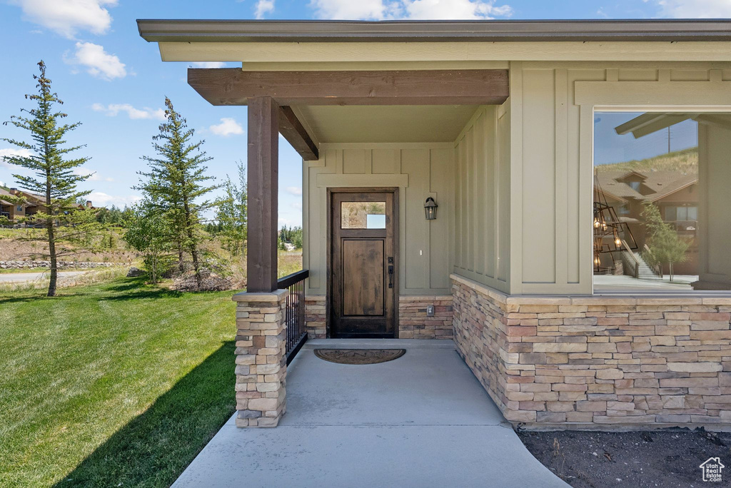 Entrance to property with board and batten siding and a yard