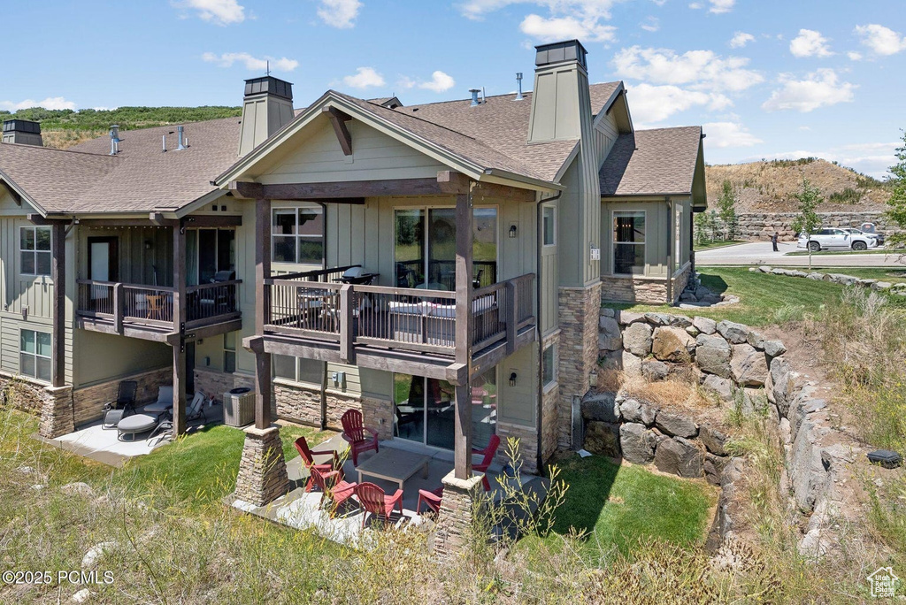 Back of house with a chimney, roof with shingles, board and batten siding, and stone siding