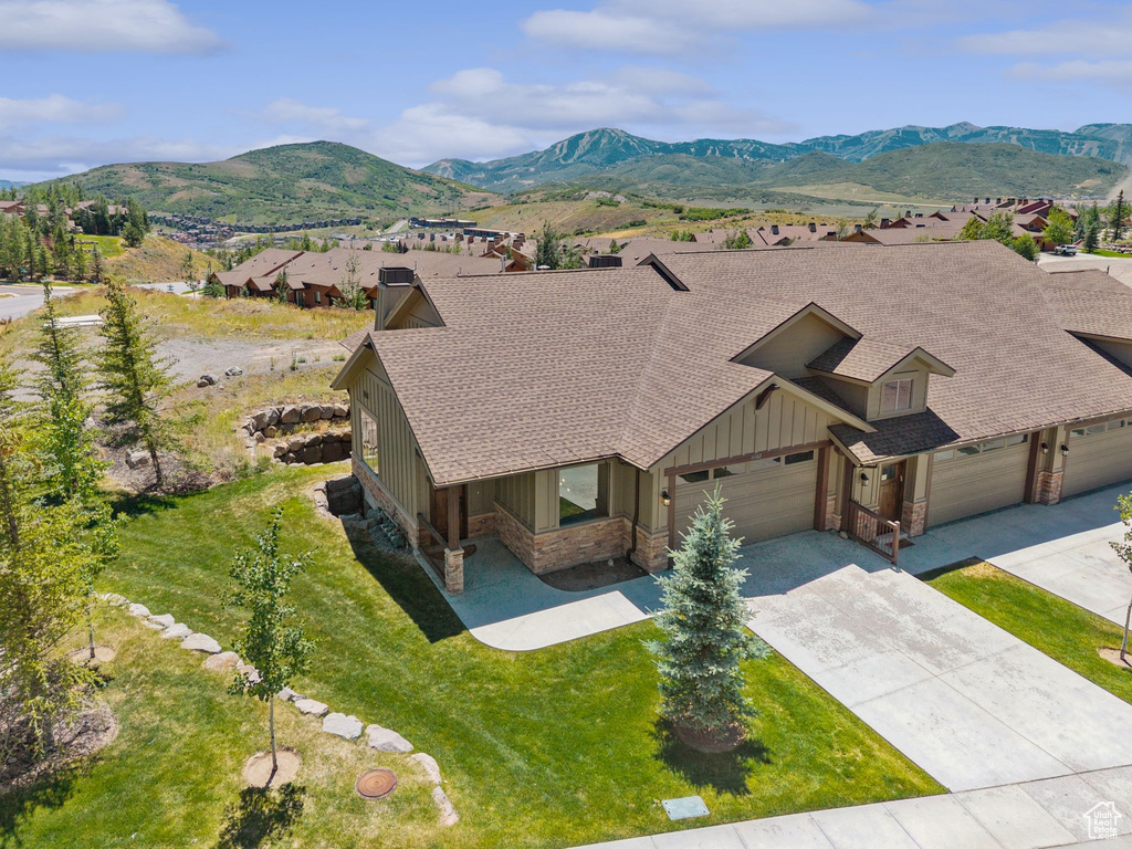 View of front of house featuring board and batten siding, a shingled roof, concrete driveway, and stone siding