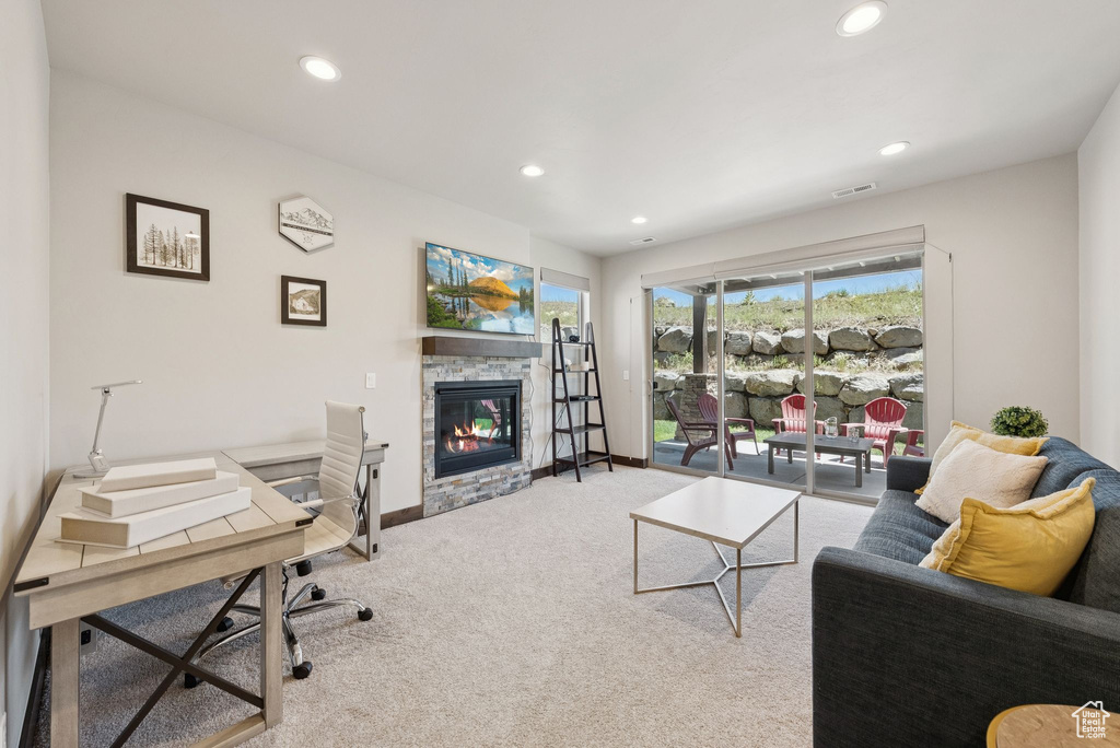 Carpeted living room with a stone fireplace, recessed lighting, and an office area