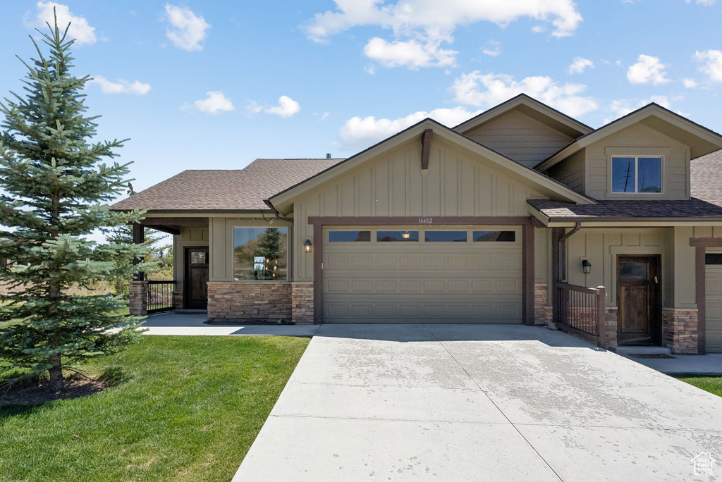 Craftsman house featuring board and batten siding, stone siding, an attached garage, and concrete driveway