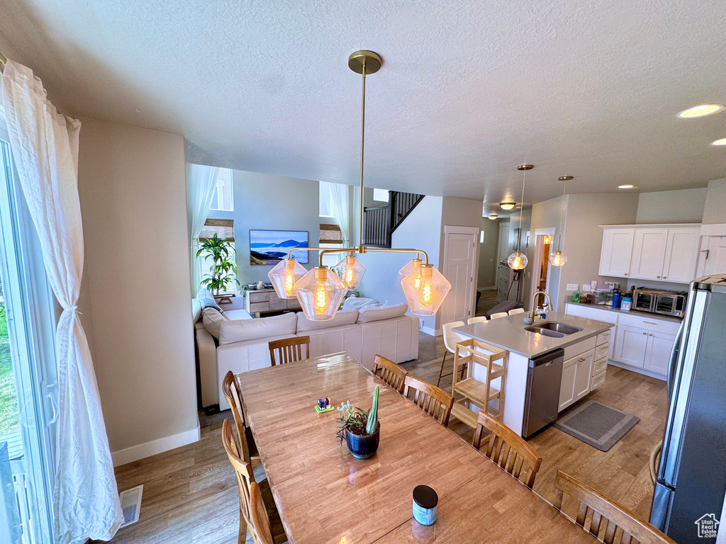 Dining area with light wood-style flooring, a textured ceiling, recessed lighting, and stairs