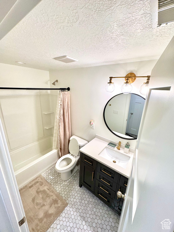 Full bathroom with vanity, shower / bathtub combination with curtain, and a textured ceiling