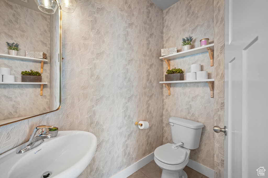Half bathroom with wallpapered walls and tile patterned floors