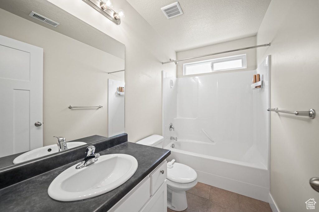 Bathroom with vanity,  shower combination, tile patterned floors, and a textured ceiling