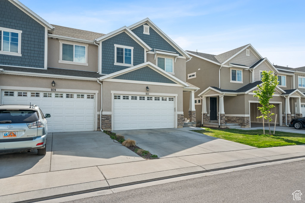 Craftsman-style home with driveway, stone siding, and an attached garage
