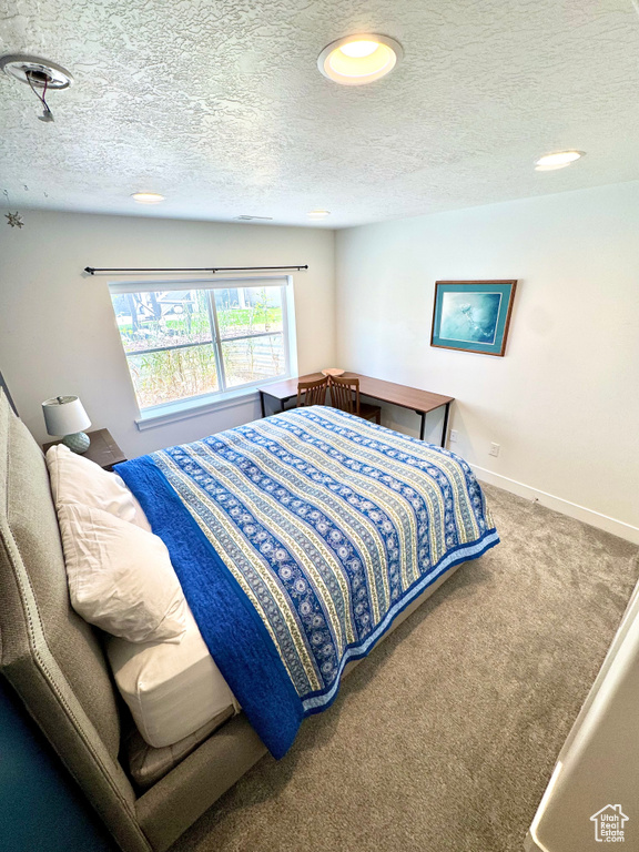 Bedroom with carpet, a textured ceiling, and recessed lighting