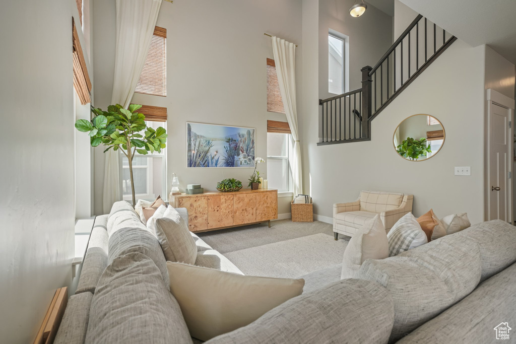 Carpeted living room featuring a towering ceiling and stairs